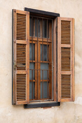 Traditional wooden shuttered window in Neve Tzedek, Tel Aviv-Yafo, with iron bars and textured stucco wall, showcasing classic Israeli architecture
