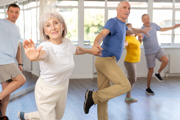 Elderly men and women learn energetic twist dance in choreography studio