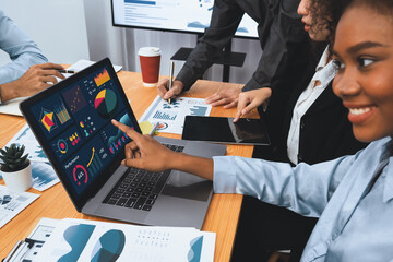Multiracial analyst team use BI Fintech software to analyze financial data on meeting table. Financial dashboard data display on laptop screen with analyzed chart for marketing indication. Concord