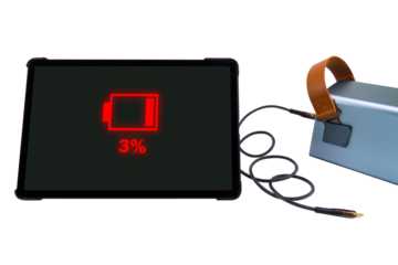 Tablet PC next to a large power bank (charging station) with a USB cable on a transparent background. On the tablet PC screen there is a red battery charge indicator of 3% (low charge)