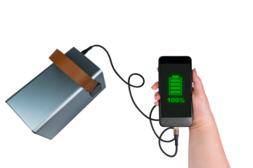 The smartphone in the hand is charged from a large power bank (charging station) via a USB cable on a transparent background. On the smartphone screen there is a green indicator of 100% battery charge