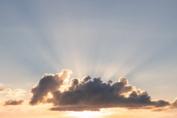 Fototapeta na wymiar Sky with a cloud and sunbeams breaking through. Sunset with sunbeams