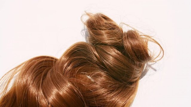 Close up of a bunch of locks of brown hair. Brown shiny wavy hair isolated on white background. Hair color palette. Haircut, hair care and beauty salon. High quality 4k footage