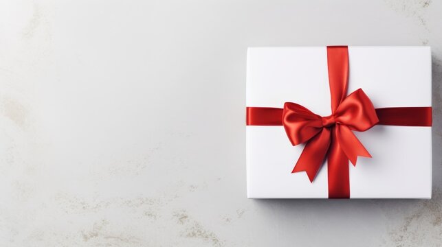 Elegant white gift box with red ribbon on a light background. Perfect present packaging with a bow for special occasions. Classic gift box design for holidays and celebrations.