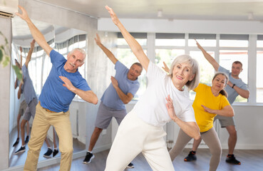 Fototapeta na wymiar Elderly woman dances energetic modern dances in group in studio