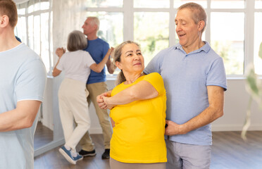 Smiling elderly woman with male partner in latin dance class. Social dancing concept