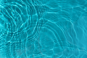 Transparent turquoise clear water surface texture with ripples, waves and rings in sunlight....