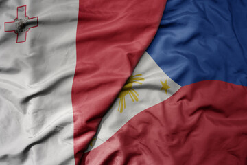 big waving national colorful flag of philippines and national flag of malta.