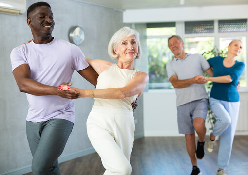 African American man is enjoying his hobby of dancing salsa with his elderly partner at fitness class, relishing in movement and activity. It great way for them to stay active and have fun together.