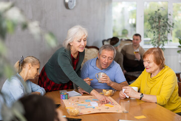 Group of positive older people playing tabletop game