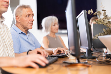 Curious mature man engaged in IT training during computer courses for adults