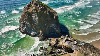 A beautiful aerial view of haystack rock at low tide as the Pacific Ocean meets the Pacific...
