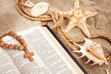 Bible book, wooden cross on sandy beach