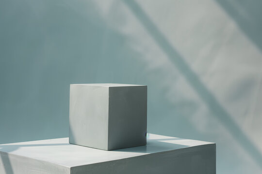 A minimalist photo of a gray cube against a gray background.