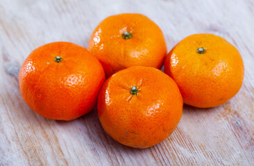 Closeup of four fresh whole clementines on wooden background. Concept of health benefits of citrus © JackF