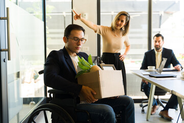 Man in a wheelchair getting fired by his female boss in an office