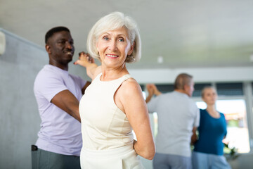 African male novice student of fitness studio practices paired Latin American rumba dance with...