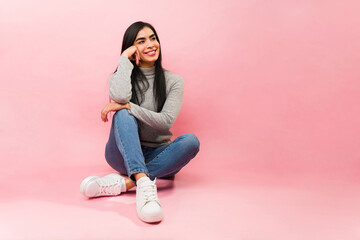 Relaxed thoughtful hispanic woman in a pink background