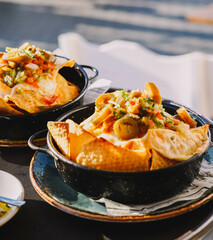 Un plato de nachos con queso, carne y guacamole
