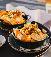 Un plato de nachos con queso, carne y guacamole
