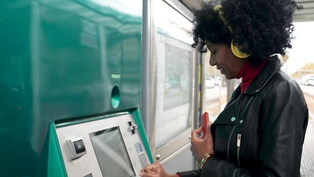 Middle-aged African American woman in a city buying a public transportation ticket in a city. Public transportation concept