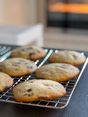 Close up of fresh baked chocolate chip cookies on baking rack on kitchen table, blurry background