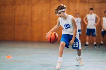 A junior basketball player is dribbling a ball and learning moves.
