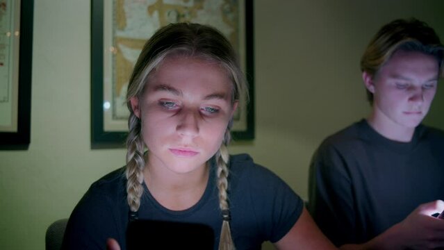 Teenager stares at a smartphone while eating a family dinner
