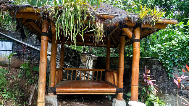 Traditional bamboo hut with thatched roof, used as a covered outdoor sitting and eating area for home or resort use.