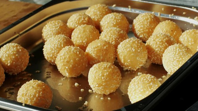 Traditional Chinese food Jian dui or sesame ball close-up. Fried Chinese pastry made from glutinous rice flour with sesame seeds. Local street food market outdoor