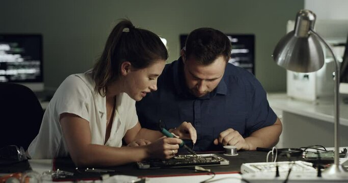 Soldering, motherboard circuit and people repair computer hardware, electronics or maintenance of semiconductor chip. IT specialist, tech industry and team collaboration on fixing microchip at night