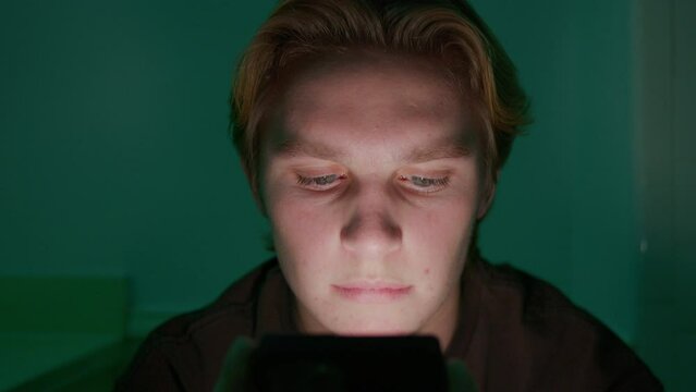 Tight shot of a man's face lit up by the screen of a smartphone