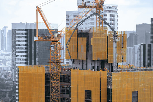 Image of exterior skyscrapers construction site with tower cranes. Cityscape under construction with cranes working moving to renovate building. Blue sky background. Architectural. Ornamented.