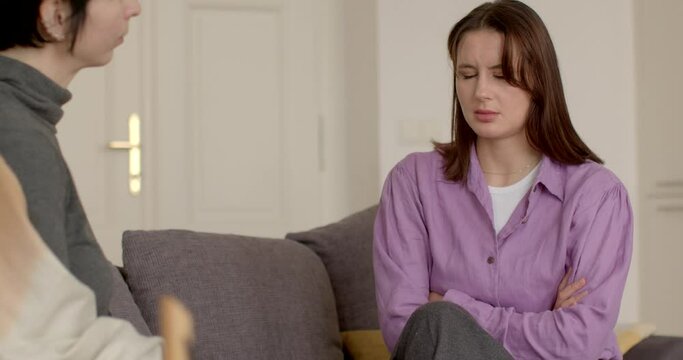 Woman client in psychotherapy session in closed posture, recalls negative experiences and struggles with trust. Therapist or counselor and client addressing emotional, psychological, behavioral issues