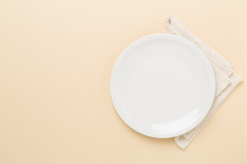 Empty plate with tablecloth on color background, top view