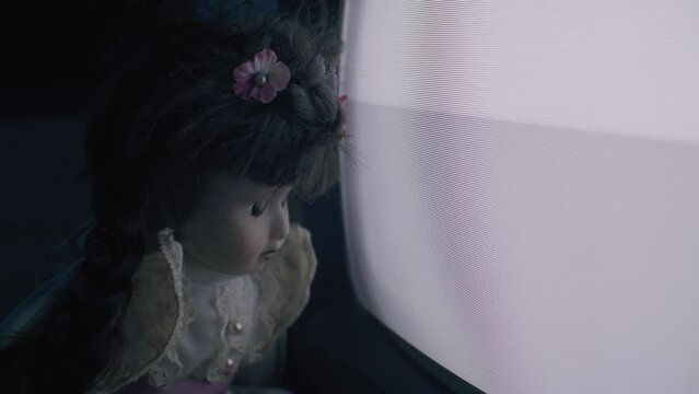 Creepy porcelain doll watching noise in TV.