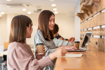 オフィス・カフェでパソコンを使いながらミーティングするビジネスウーマンの女性たち
