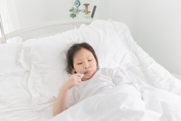 asian children has fever and admit in hospital, she measure temperature with digital medical...