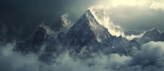 A large mountain is shrouded in clouds under a cloudy sky, creating a dramatic and mystical scene in the majestic landscape. The mountain appears formidable and imposing against the overcast backdrop.
