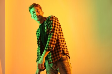 Young man dancing on color background in neon lights