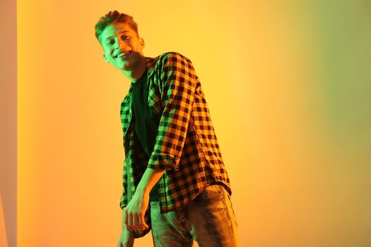 Young man dancing on color background in neon lights