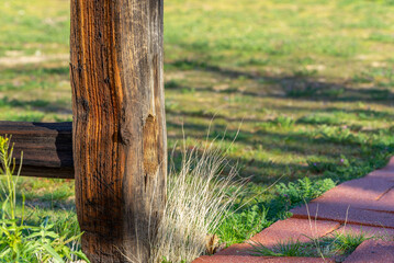 Wooden fence post with texture and green grass in the background