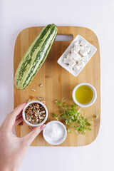 Cucumber Salad with White Cheese and Nuts Ingredients on a wooden chopping board and white background