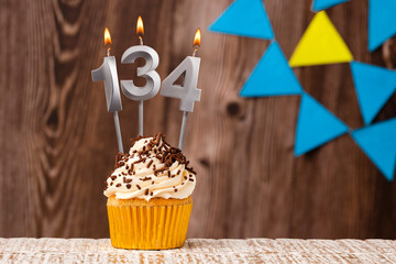 Birthday card with candle number 134 - Wooden background with pennants