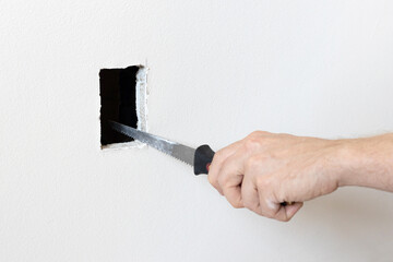 Cutting hole in the drywall. Electrician using drywall knife to cut a hole - obrazy, fototapety, plakaty