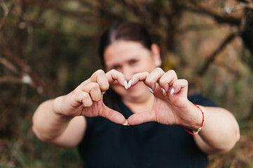 A woman makes a heart shape with her hands in the Paramo of Colombia, expressing love for the...