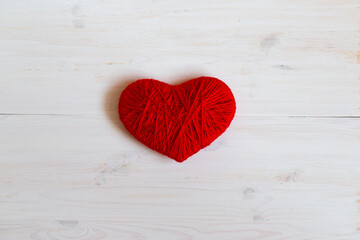 Red heart shape made from wool on white wooden background