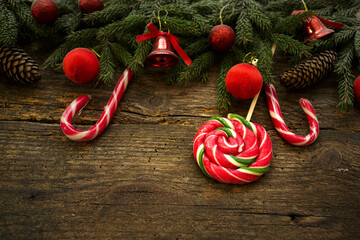 Christmas border with fir tree branches, cones, christmas decorations and candy cane on rustic wooden boards