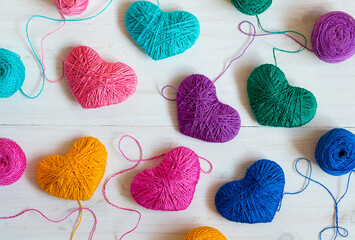 Multicolored Hearts with a balls of thread on white wooden background