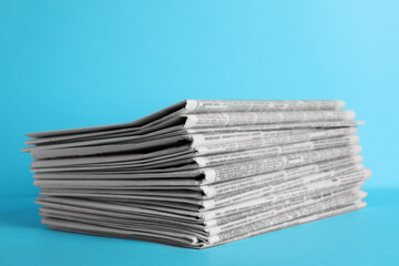 Stack of newspapers on light blue background. Journalist's work